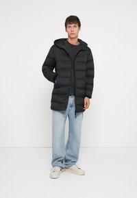 Mustapuffatakki hupulla, tikattu muotoilu, vetoketjusulku ja kaksi sivutaskua. Omaavat hieman ylisuuren istuvuuden ja pehmeän kankaan.