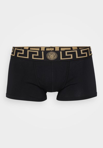Melna bokserveida apakšveļa ar zelta ģeometrisku rakstu jostasvietā un medaljonu logo centrā. Mīksts kokvilnas materiāls ar piegulošu piegriezumu.