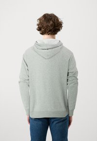 Sudadera con capucha de color gris claro con un ajuste relajado, que incluye una capucha con cordón, puños y dobladillo acanalados. Fabricada con una tela suave y texturizada.