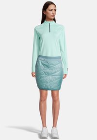 Top de cremoso color aguamarina de manga larga y cremallera combinado con una falda acolchada de longitud media en color teal, con una textura suave y una cinturilla en contraste.