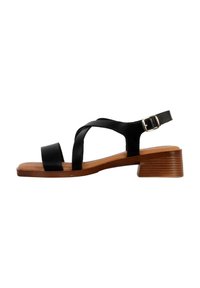 Sandal in pelle nera con cinturini incrociati, una cinghia alla caviglia con fibbia e un tacco basso in legno con finitura testurizzata.