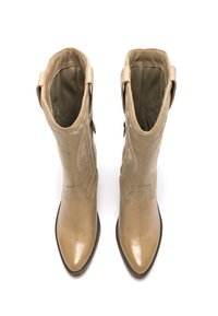 Stivali alti fino al ginocchio in pelle beige con dettagli cuciti, punta a punta e chiusura con zip laterale. Tessuto liscio con una finitura leggermente lucida.