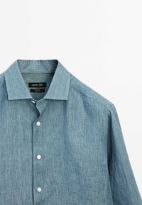 Chemise en lin bleu clair à manches longues avec col et boutons blancs sur fond blanc.
