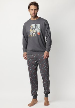 Camisa gris de manga larga con un diseño gráfico que incluye personajes y texto, combinada con pantalones grises decorados con pequeños patrones de estrellas rojas y azules.
