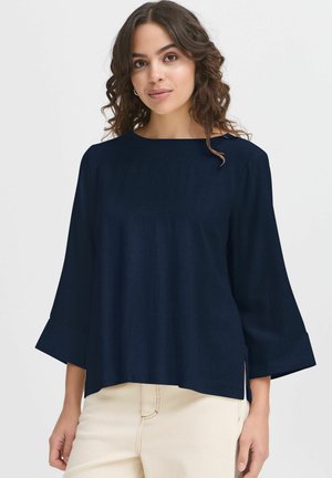Navy blue, lightweight top with a boat neckline, flared 3/4 sleeves, and side slits; smooth texture and minimal detailing.