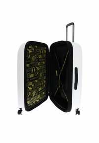 Valise rigide blanche avec un intérieur à motif noir et jaune, comprenant deux compartiments et une poignée rétractable.