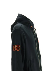 Felpa nera con zip e numero "68" arancione sulla manica, con estremità dei lacci arancioni abbinati e tasche frontali, mostrata di lato su sfondo bianco.