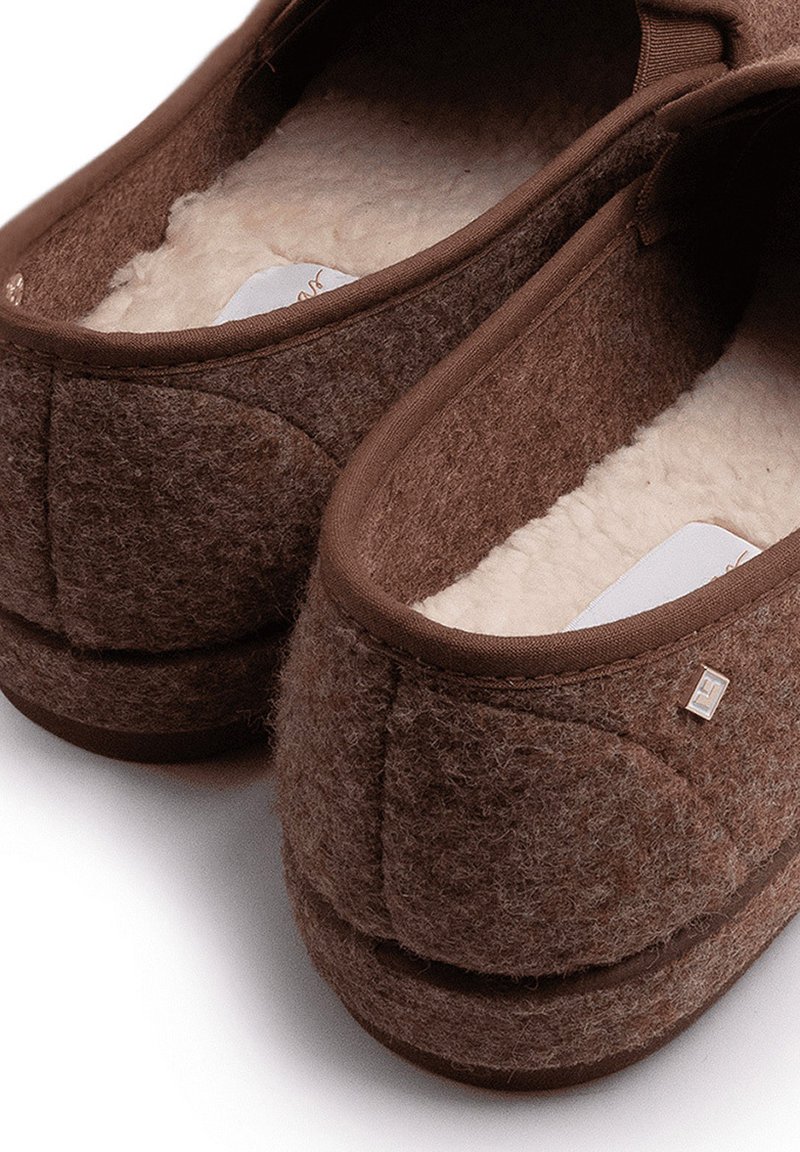 Braune Filzschlappen mit weichem weißen Fleecefutter und gepolsterten Fersen, entworfen für Komfort und Wärme im Innenbereich.