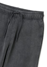 Dunkelgraue Jogginghose mit elastischem Bund, Kordelzugverschluss und zwei Seitentaschen. Weiche Textur, leicht angeraute Oberfläche.