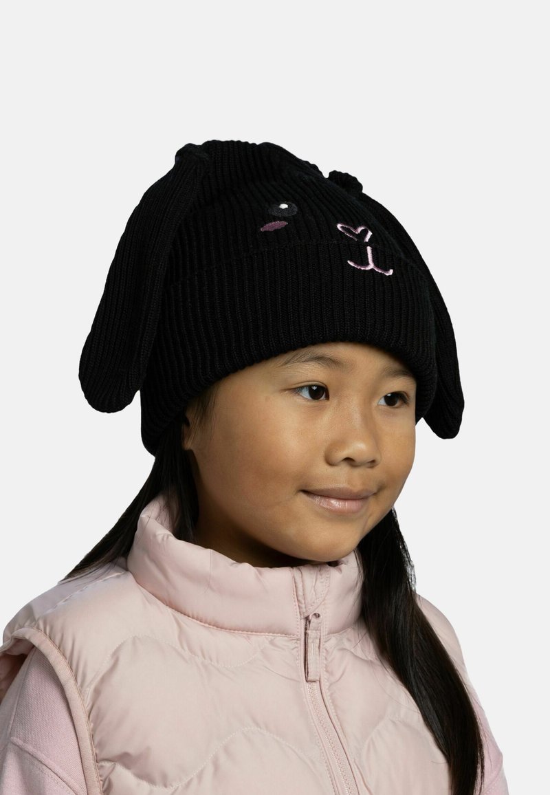 Black knitted beanie featuring bunny ears, embroidered facial features in beige and pink, ribbed texture, worn over a light pink puffer vest.