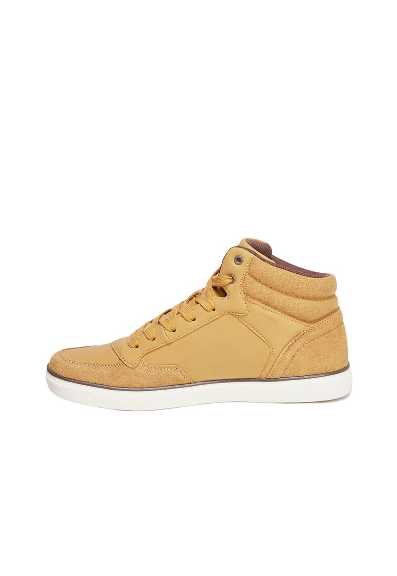 Zapatilla alta en color marrón, fabricada con materiales de ante y cuero, con diseño de cordones, cuello acolchado y suela de goma blanca. Se puede ver el detalle del panel lateral.