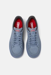 Sneakers in suede azzurro chiaro con accenti grigi, lacci piatti e solette rosse con il logo "Camper". Punta arrotondata e suola in gomma.
