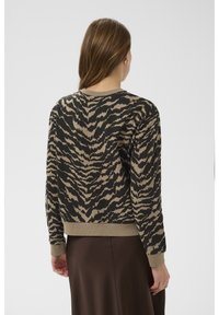 Mikina se zvířecím potiskem v černo-béžovém vzoru, s žebrovaným lemem a manžetami, z měkké látky, s kulatým výstřihem. Nošena přes hnědou sukni.