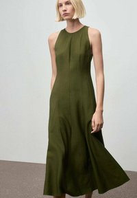 Vestido sin mangas de color verde oscuro, hecho de una tela texturizada, con un corpiño ajustado y una falda acampanada hasta la rodilla que cuenta con bolsillos laterales.
