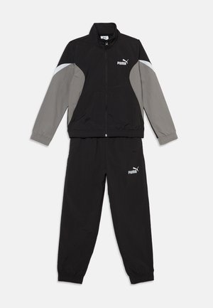 Survêtement Puma noir et gris avec veste zippée et poignets élastiques, présenté à plat sur fond blanc.