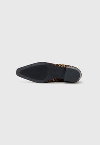 Semelle en caoutchouc noire d'une chaussure à talons avec une tige imprimée léopard. La semelle a une finition lisse et un léger motif de grip texturé.