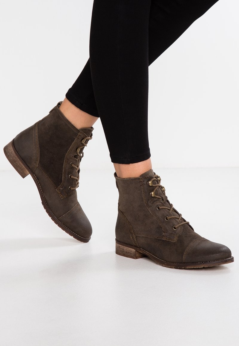 Bottines marron à lacets en daim, avec un bout arrondi, un petit talon bloc, des œillets métalliques pour les lacets, et une finition texturée.