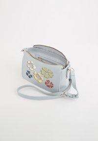 Geantă de mână din piele de culoare albastră deschisă, cu broderie florală în galben, alb, verde, roșu și albastru. Dispune de o curea de umăr și două compartimente cu fermoar.