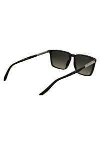 Lunettes de soleil noires et écaille de tortue avec des verres rectangulaires, des verres dégradés gris foncé, des branches noires fines et des accents argentés subtils sur les charnières.