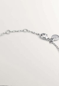 Collar de cadena de plata con eslabones redondos y ovalados, con cierre de langosta y colgante circular. Textura suave, acabado brillante.