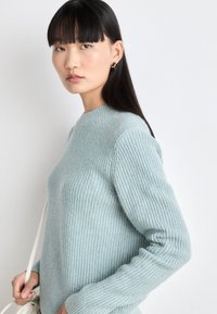 Hellblauer Strickpullover mit geripptem Muster und rundem Halsausschnitt. Lange Ärmel und lockere Passform. Minimalistisches Design ohne Muster.