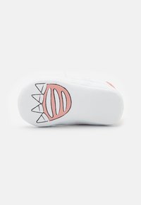 Weiße Gummisohle mit einem rosa Design, das ein verspieltes Muster aus Zähnen und Streifen zeigt, strukturiert für Grip und Flexibilität.
