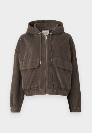 Brun fløjljakke med hætte, frontlynlås, store lappelommer, elastiske manchetter og et cropped design. Blød tekstur med lodrette riller.
