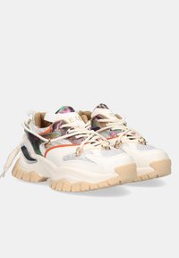 Zapatillas blancas voluminosas con acentos iridiscentes, paneles de malla, detalles en naranja y verde, suelas texturizadas en beige y herrajes decorativos.