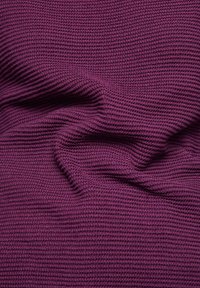 Lila strukturiertes Strickgewebe mit geripptem Muster, das subtile wellenartige Falten und ein weiches Erscheinungsbild zeigt.