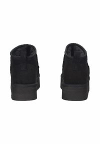 Un paio di stivali neri alla caviglia con suole spesse, linguette per il tiraggio e un interno morbido, mostrati da dietro su uno sfondo bianco.