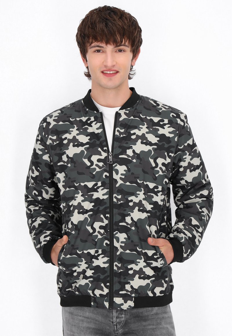 Camouflage bomberjack in grijs- en zwarttinten, met een rits aan de voorkant, geribbelde manchetten en twee zijzakken. Glad synthetisch materiaal.