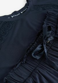 Navyblauw top met kanten details op de schouders en een gestructureerd, geplisseerd ontwerp bij de taille met een bijpassende strik.