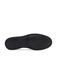 Suela de zapato de goma negra con un patrón texturizado, que presenta ranuras y elementos de diseño en forma circular. Los bordes son suaves y redondeados.