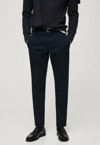 Pantaloni bleumarin cu o croială ajustată, dintr-o țesătură de bumbac netedă, cu bucle pentru curea și buzunare frontale, asortați cu pantofi din piele negri.