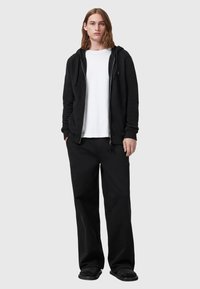Black zip-up hoodie with a kangaroo pocket, paired with a white crew neck t-shirt and black wide-leg pants. Smooth fabric, relaxed fit.