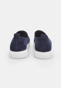 Marineblaue Wildleder-slipper mit einer weißen Gummisohle, die eine hintere Zuglasche und eine strukturierte Oberfläche aufweisen. Glatte Innenauskleidung.