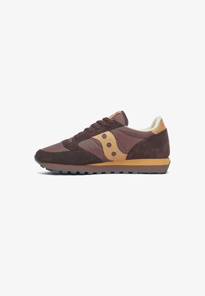 Sneaker in suede marrone con dettagli in beige, caratterizzata da un logo rotondo, un profilo basso e una suola in gomma resistente con battistrada testurizzato.