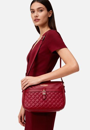 Borsa a tracolla rossa in pelle trapuntata con chiusura a fibbia dorata e tracolla regolabile, caratterizzata da una forma rettangolare e una texture liscia.