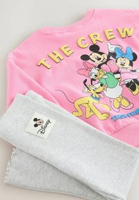 Hanorac roz cu textul "THE CREW" și grafică cu personaje Disney. Pantaloni gri cu revere, având un etichetă albă cu logo-ul lui Mickey Mouse.