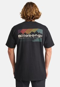 Black cotton t-shirt featuring a colorful mountain graphic and "Billabong Adventure Division" text in a contrasting design on the back.