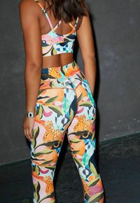 Färgglad sport-bh och höga leggings med ett blommigt och djurmönster i nyanser av orange, grönt, blått och svart.