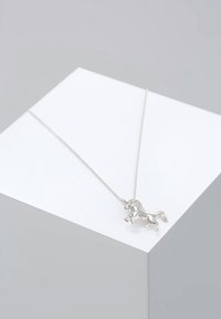 Zilveren ketting met een eenhoorn hangertje, gedetailleerde manen en lichaam, hangend aan een fijne ketting, gepresenteerd op een minimalistisch platform.