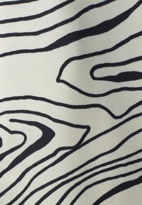 Abstracte stof met een crèmekleurige achtergrond en gedurfde zwarte houtnerfspatronen. Glad oppervlak en vloeiend ontwerp met variërende lijndiktes.