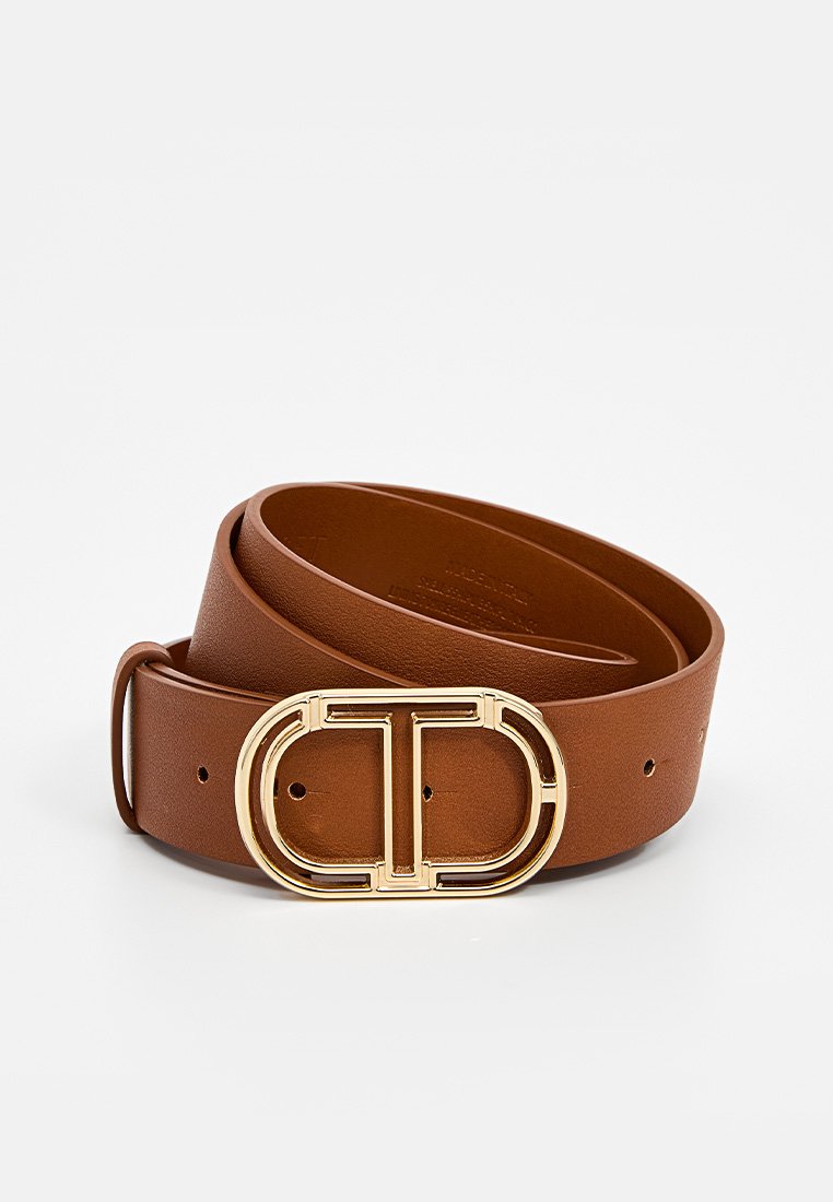 Brown leather belt with a gold circular buckle featuring a raised logo design. Smooth texture, with multiple adjustment holes.
