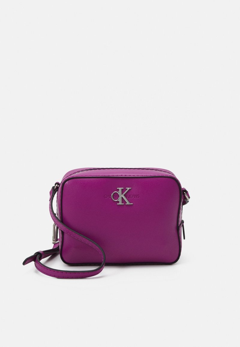 Fialová kožená crossbody taška obdélníkového tvaru, se stříbrným logem, zipovým zapínáním a nastavitelného popruhem. Hladká textura, elegantní design.