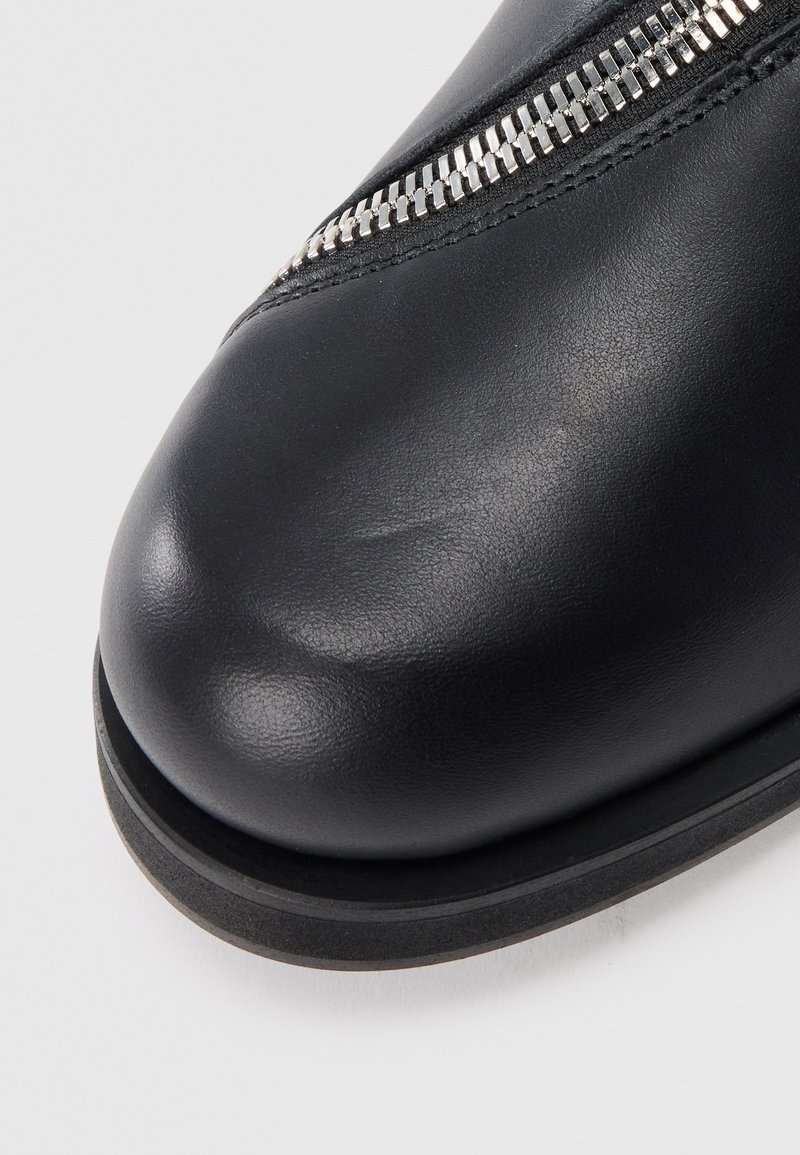 Stivale in pelle nera con punta arrotondata, dotato di una cerniera in metallo argento lungo il lato e una superficie texturizzata.