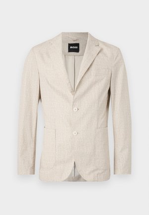 Blazer bege claro com um tecido texturizado, lapelas com corte em ângulo, dois bolsos frontais e dois botões. O interior possui um forro contrastante.
