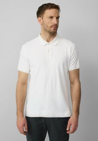 Witte poloshirt met een gestructureerd patroon, korte mouwen en een klassieke kraag. Gemaakt van een lichtgewicht stof. Geen zichtbare logo's of accenten.