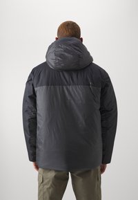 Black puffer jacket with a large hood, featuring a matte texture and contrasting dark panel on the upper back. The sleeves are also black.