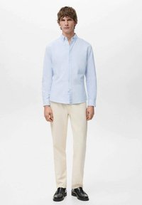 Blauw-wit gestreept overhemd met knopen en lange mouwen, gecombineerd met crèmekleurige broek en zwarte schoenen. Eenvoudig ontwerp en lichtgewicht stof.